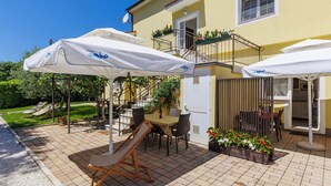 Un espace extérieur aménagé en terrasse, avec une table et des chaises, un toboggan pour enfants et des parasols.