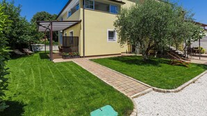 Une maison à deux étages dotée d’un patio couvert, d’une pelouse bien entretenue et d’une allée en gravier.