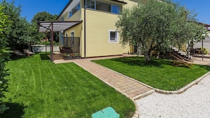 A two-story house with a covered patio, a well-maintained lawn, and a gravel driveway. - Apartment Nino by Interhome (Poreč)