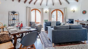 Ein gemütliches Wohnzimmer mit einer Couch, einem Esstisch, Stühlen und einem Fernseher.