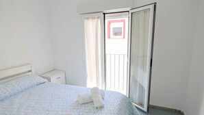 A hotel room with a bed, a bedside table, a window with curtains, and a view of the outside balcony. - Rainbow by Interhome (Benidorm)