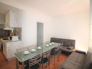Un espacio habitable compacto con una mesa de comedor, sillas, sofá, kitchenette y una puerta.