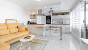 A modern kitchen with white cabinets, a dining area with a white table and chairs, and a yellow sofa. - Terrasses du Levant by Interhome (Canet-Plage)