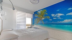 A bedroom with a bed, a window with blinds, and a beach mural on the wall. - Terrasses du Levant by Interhome (Canet-Plage)