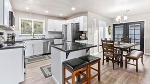 A modern kitchen with white cabinets, stainless steel appliances, and a black countertop island. - Waterviews, Gameroom, close to DT, & Ferries! (Port Orchard)