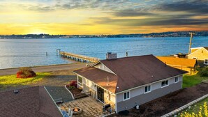 A house with a deck overlooking a waterfront, a dock, and a fire pit in the yard. - Waterviews, Gameroom, close to DT, & Ferries! (Port Orchard)