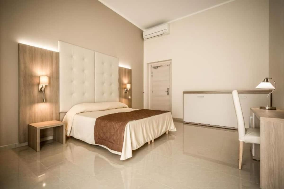 A modern hotel room with a large bed, bedside tables, a desk, and a chair.