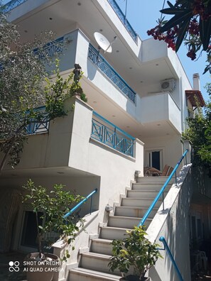 A multi-level building with a staircase, balconies, and satellite dishes.