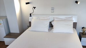 Un letto ben rifatto con lenzuola bianche e due asciugamani piegati ai piedi.