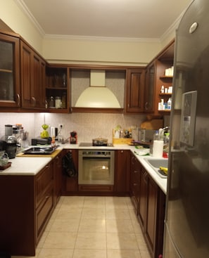 Una cocina con armarios de madera, un refrigerador de acero inoxidable, un horno y un lavaplatos.