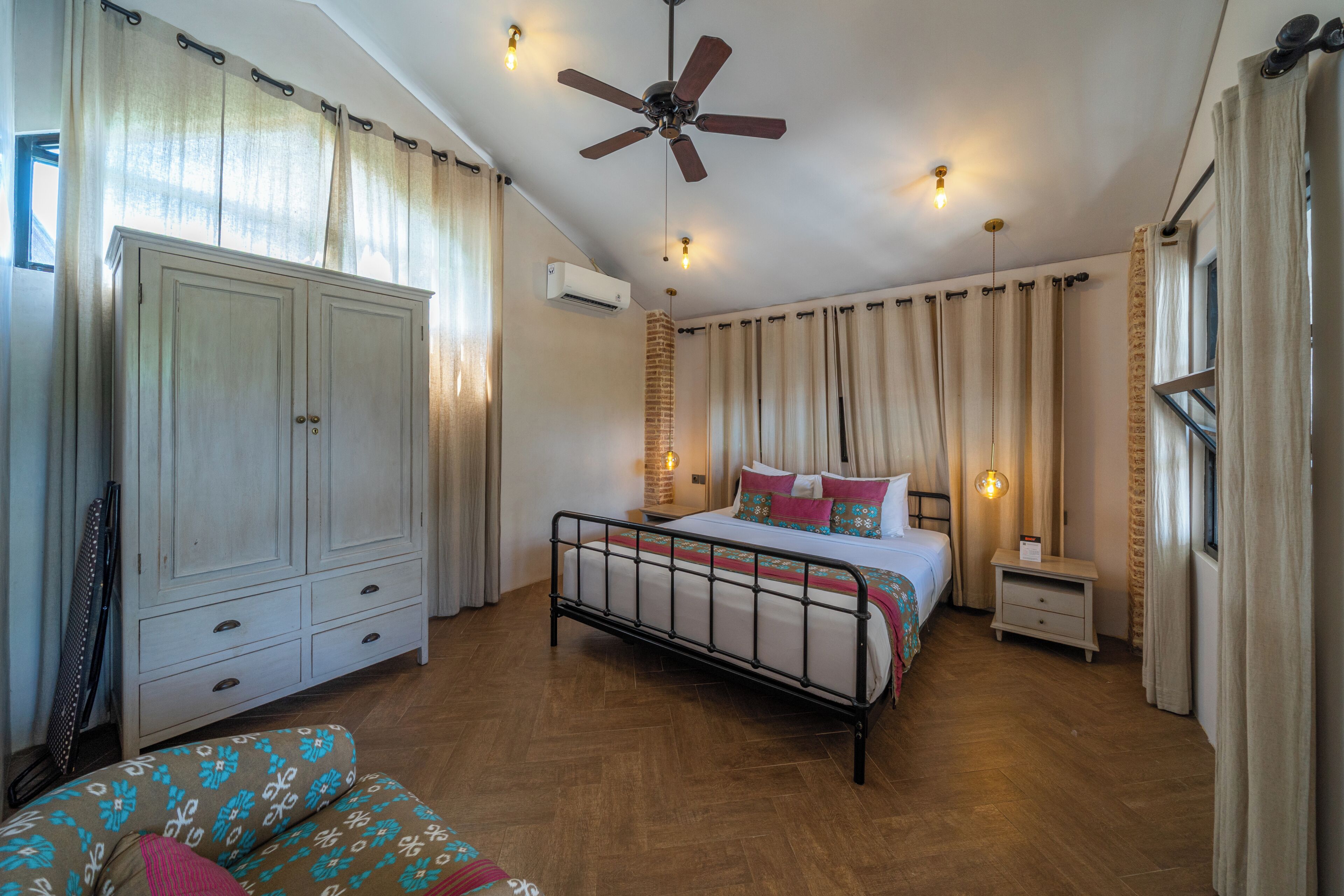 A bedroom with a bed, wardrobe, bedside table, and a ceiling fan.