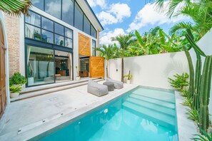 Une maison moderne dotée d’une piscine, de portes vitrées et d’une terrasse en bois.