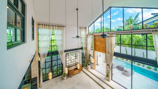 A spacious room with large windows, a ceiling fan, and a view of a swimming pool. - Villa Upeksha (Canggu)