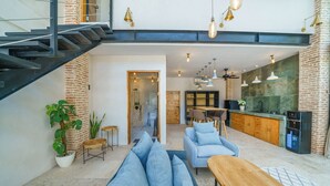 A modern interior with a staircase, seating area, kitchen, and dining space. - Villa Upeksha (Canggu)