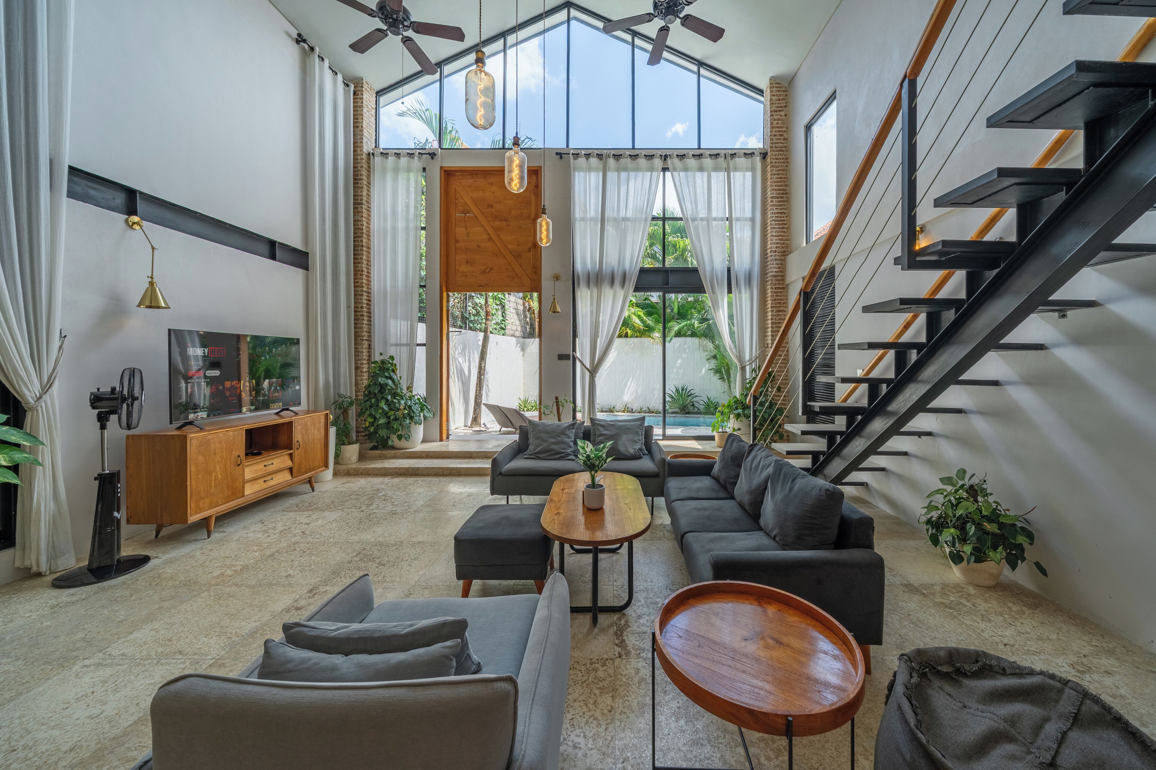 A modern living room with a sofa set, a coffee table, and a staircase.