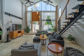 Una sala de estar moderna con un conjunto de sofá, una mesa de centro y una escalera.
