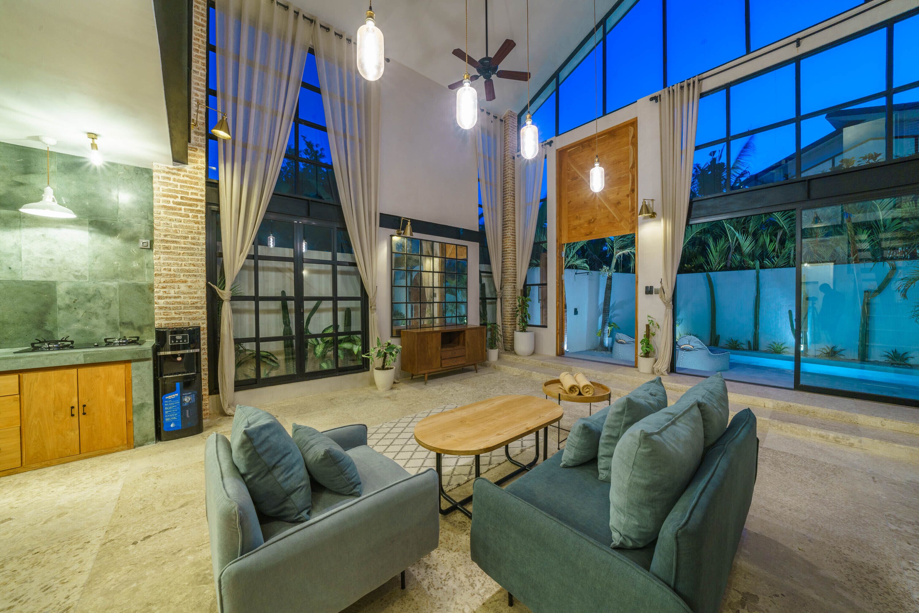 A spacious living area with a modern kitchen, comfortable seating, and large windows offering views of the outdoors.