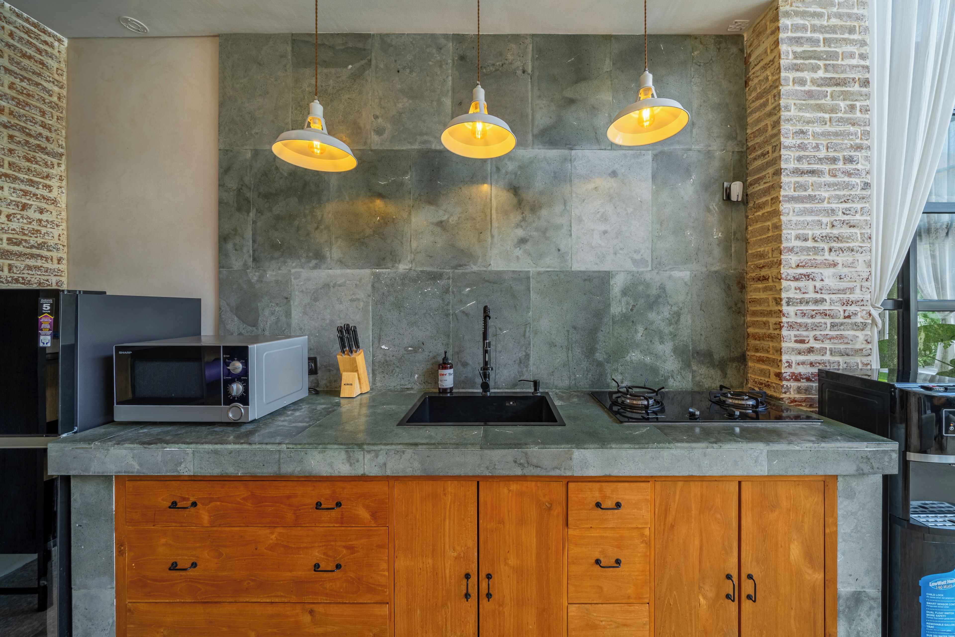 A kitchen with a built-in microwave, a sink, a gas stove, and wooden cabinets.