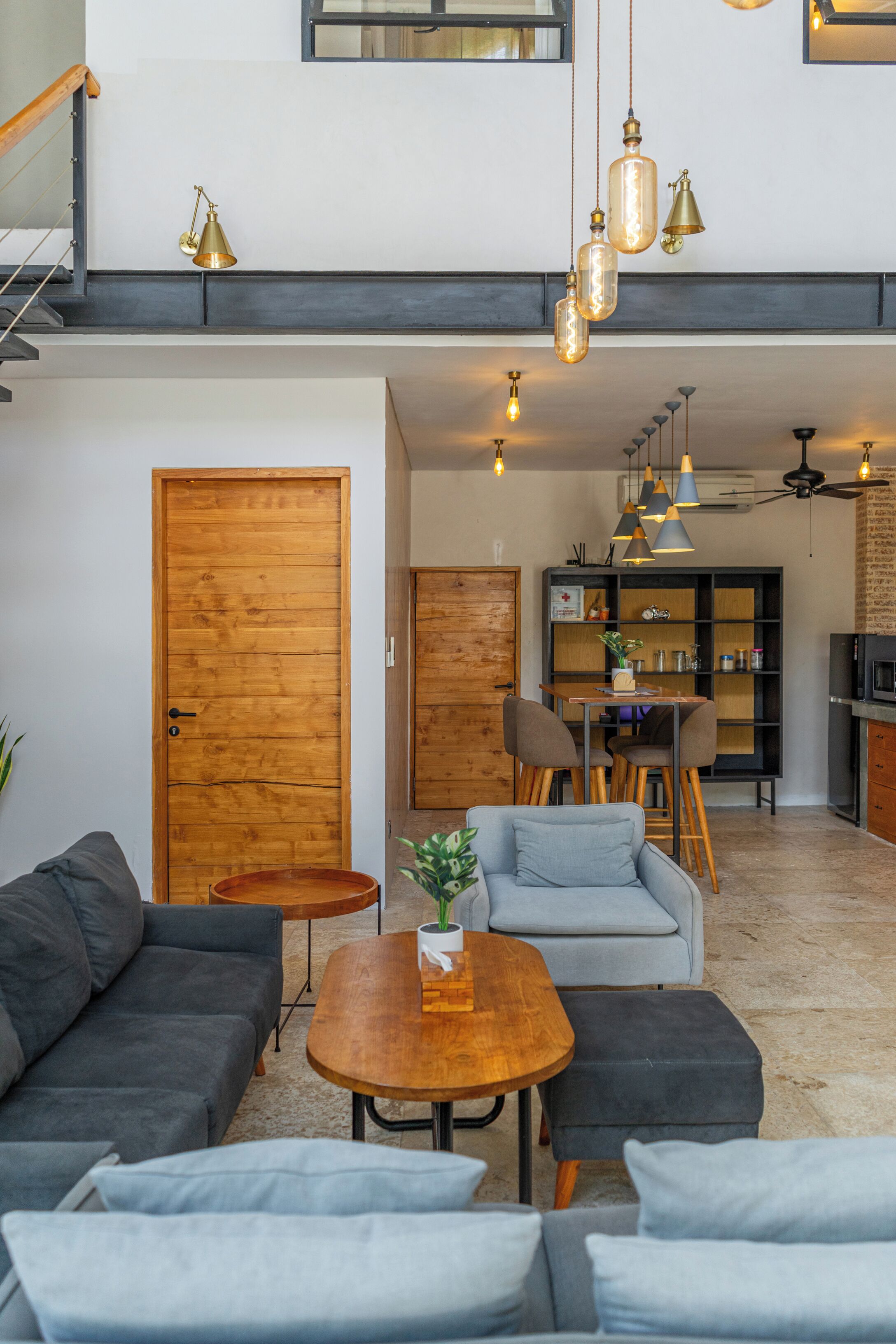 Un vaste espace de vie doté d’un haut plafond, d’une porte en bois, d’une table à manger avec des chaises, et d’un coin cuisine avec un comptoir et des armoires noirs.