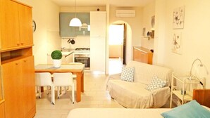 Un espacio habitable compacto con kitchenette, comedor y sofá.
