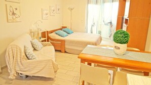 Una habitación acogedora con una cama, un sofá, una mesa de comedor y una planta en maceta.