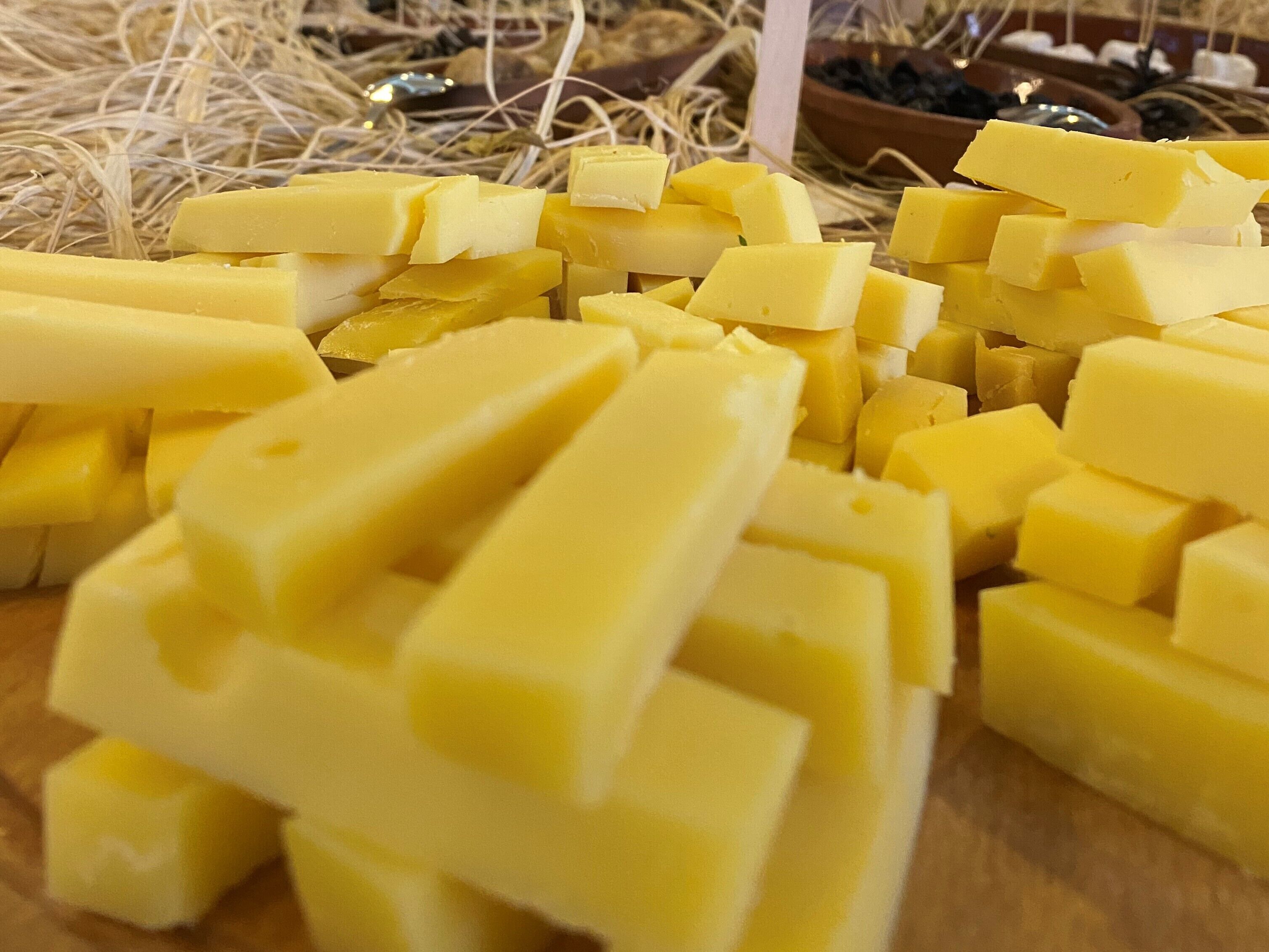 A pile of yellow cheese cubes on a wooden surface.