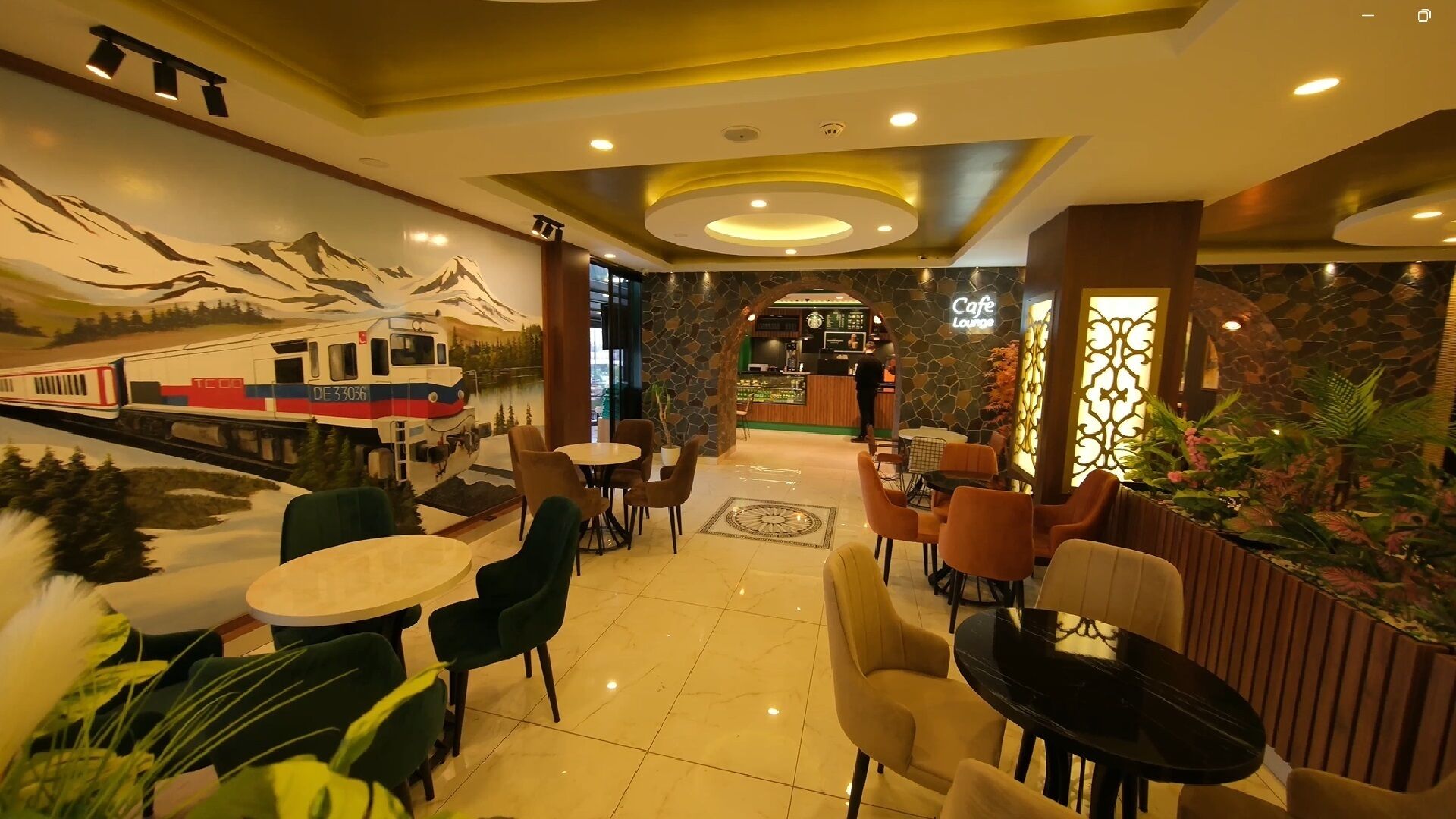 A hotel lobby with a mural of a train, seating areas, and a cafe/lounge.