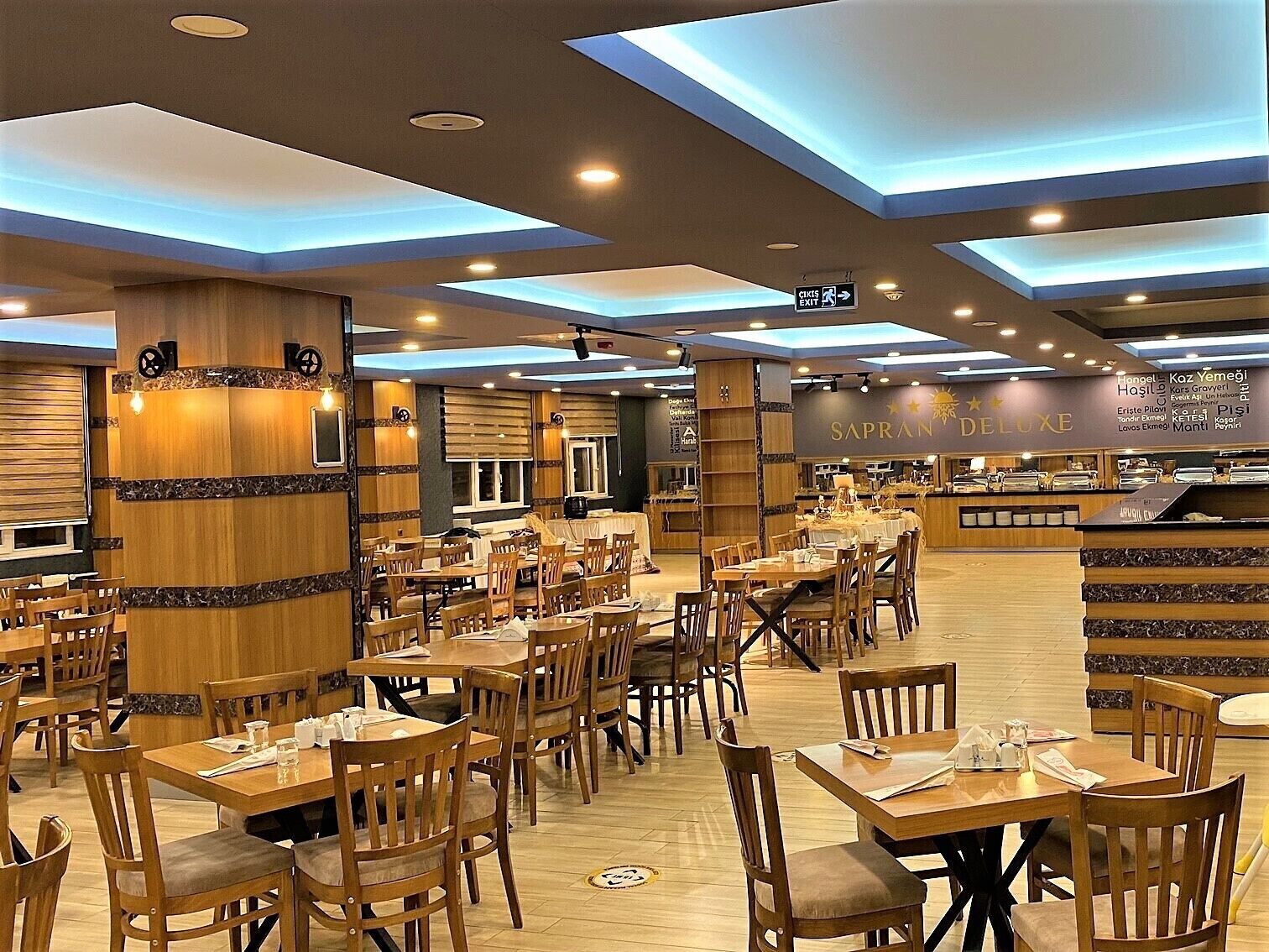 A restaurant with multiple dining tables and chairs, a counter with a menu, and a sign indicating an exit.