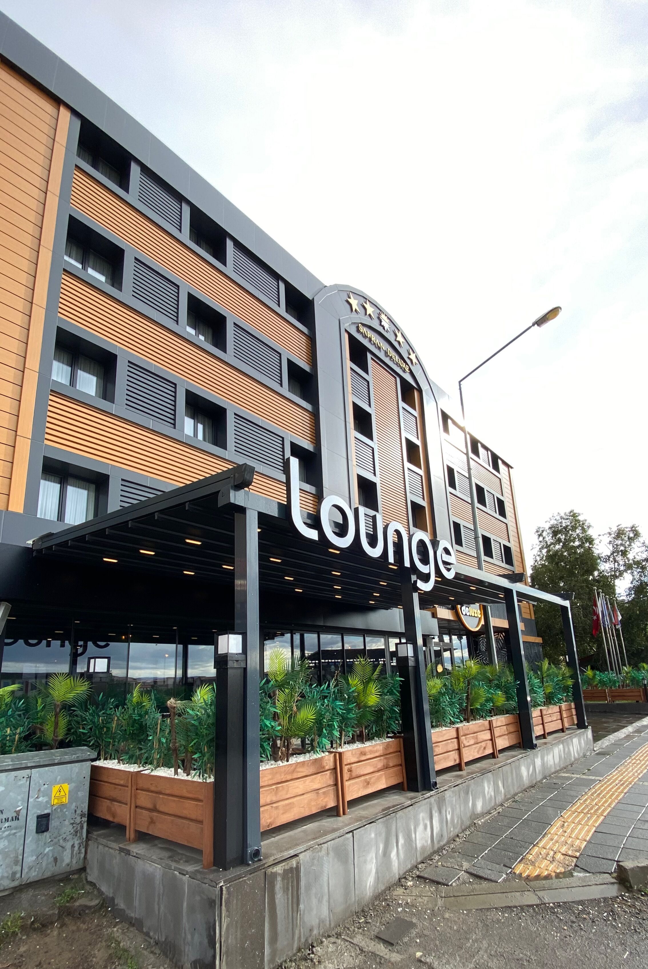 Un edificio con un letrero que indica 'lounge', con un diseño moderno que incluye paneles de madera y un área de entrada cubierta.