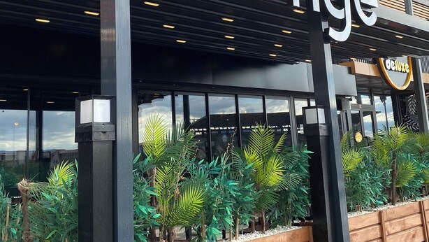 Un edificio con un letrero que dice "Deluxe Lounge" y un diseño arquitectónico moderno con paneles de madera y ventanas amplias.