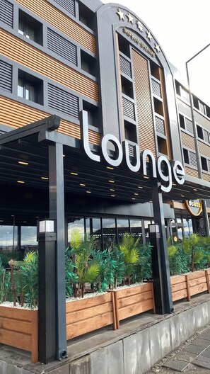 Un edificio con un letrero que dice "Deluxe Lounge" y un diseño arquitectónico moderno con paneles de madera y ventanas amplias.