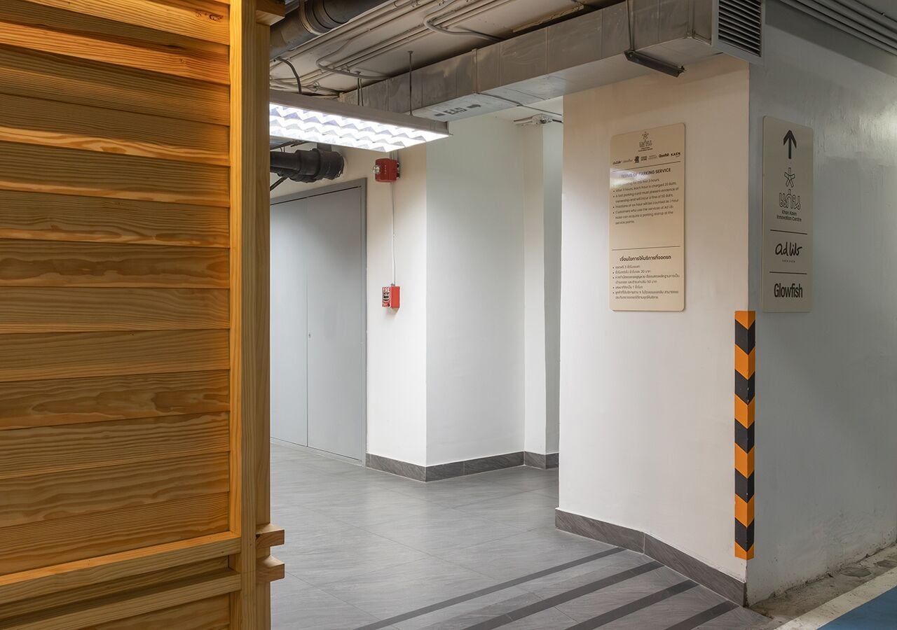 Un pasillo limpio y moderno con un marco de puerta de madera, un extintor y señales de orientación.