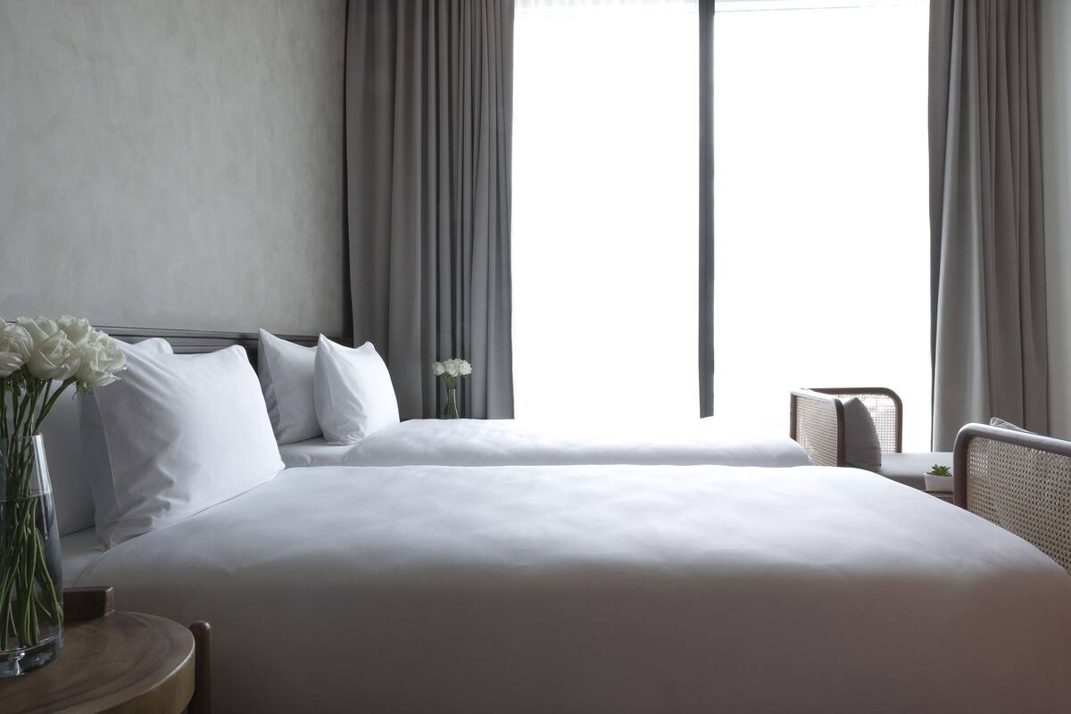 A hotel room with a large bed, a bedside table with a vase of flowers, and a chair.