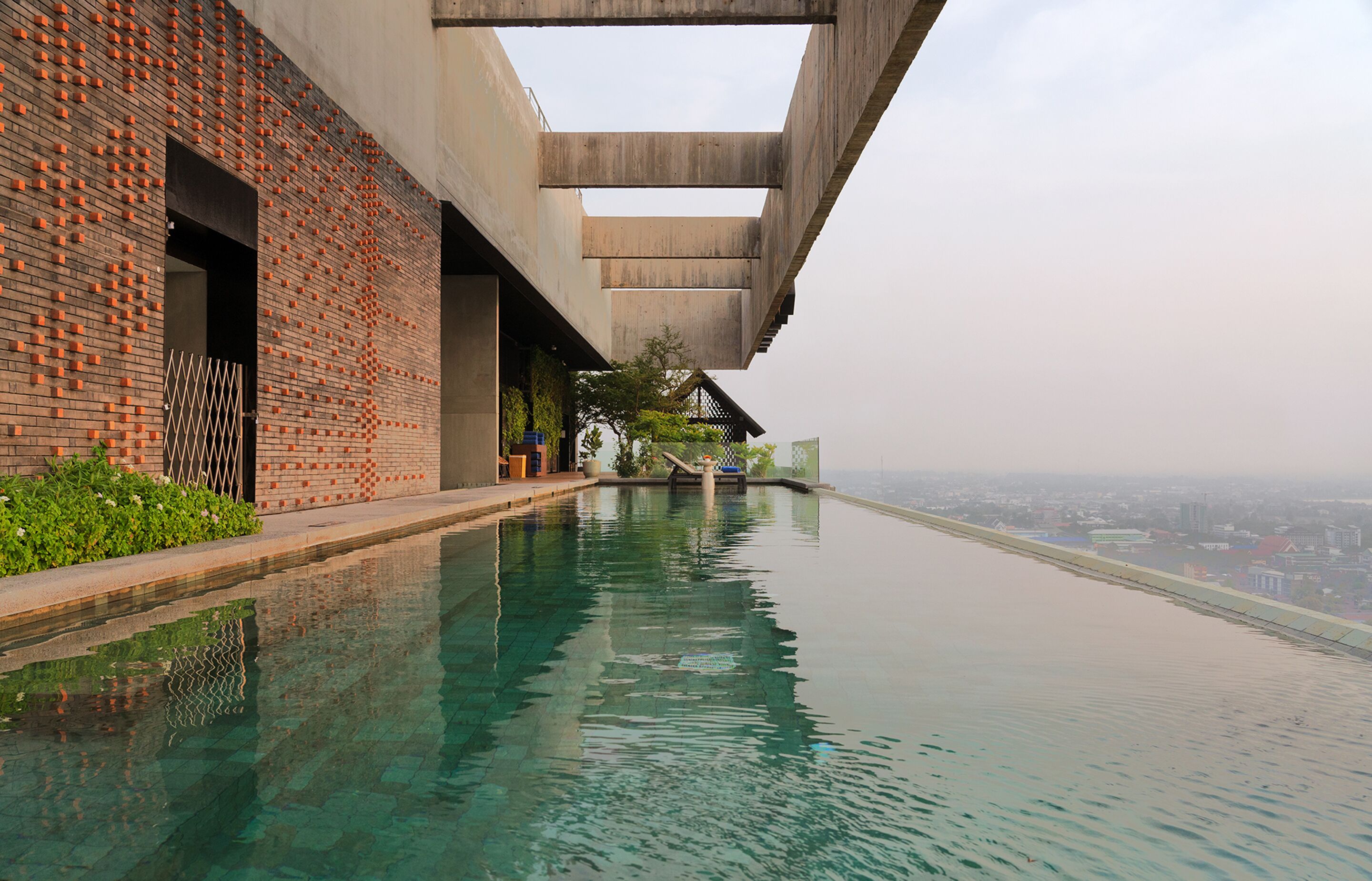 A modern building with a brick facade and a long, narrow pool extending from the structure.