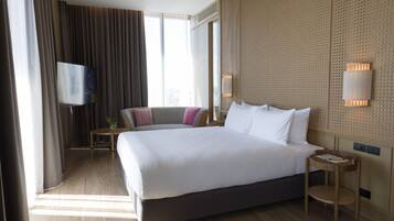 Ein Hotelzimmer mit einem großen Bett, einem Fernseher, einem kleinen Tisch und einer Wandlampe.
