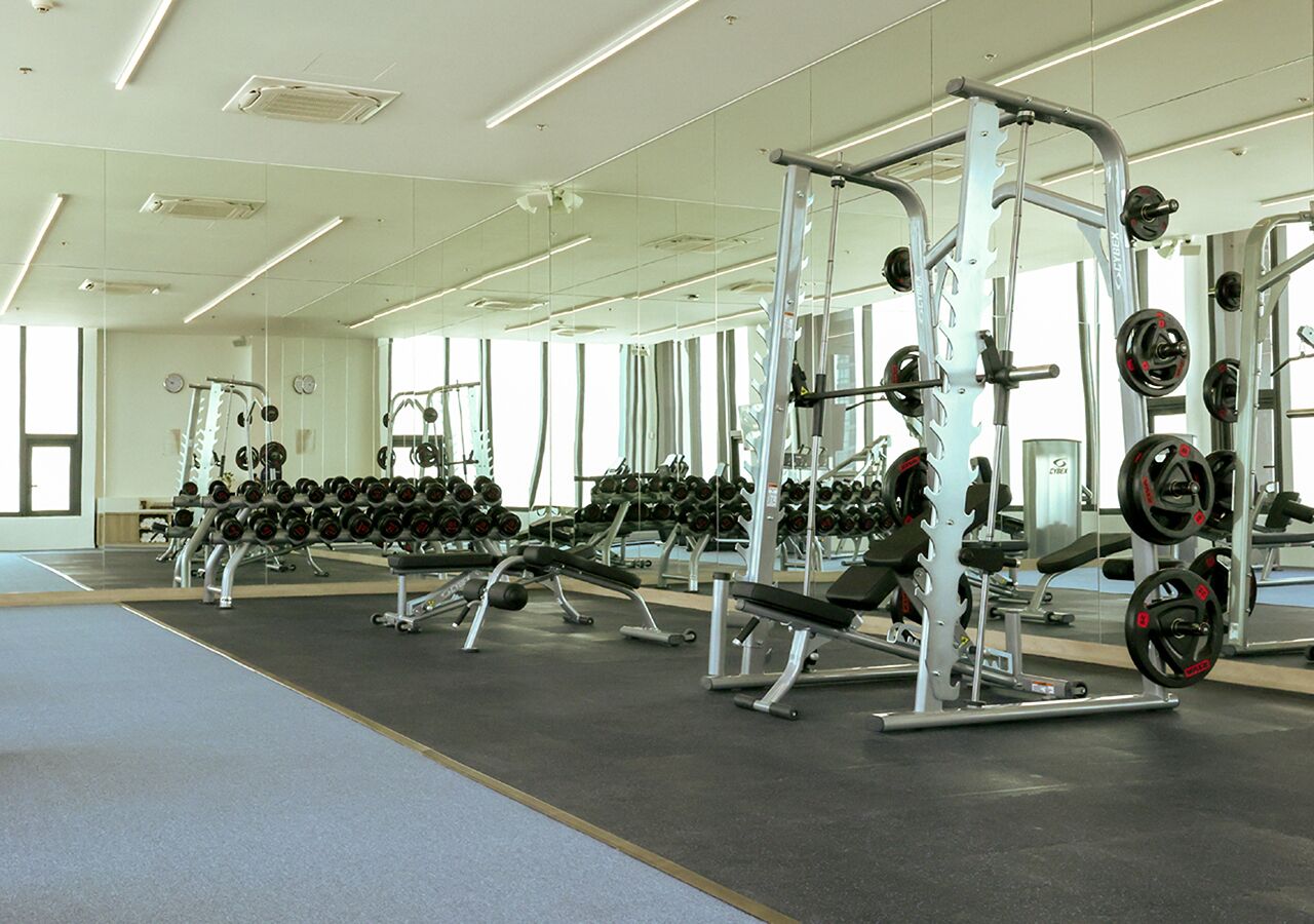 A gym with weightlifting equipment and mirrors on the walls.