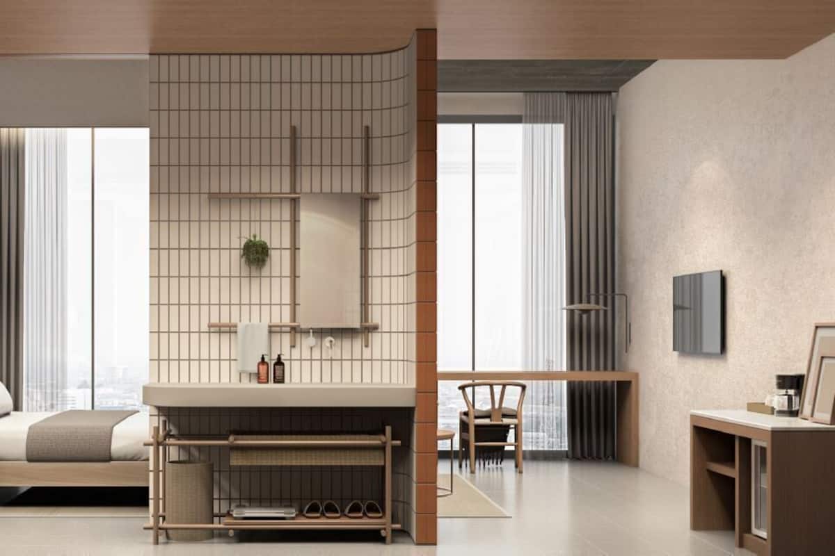 A modern hotel room with a bed, a desk, a chair, a wardrobe, and a bathroom area.