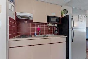 A kitchen with a microwave, stove, sink, and refrigerator.