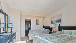 Un dormitorio con dos camas, un aparador, un cuadro y una puerta que da a otra habitación.