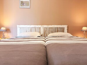 A double bed with a white headboard and two bedside lamps.
