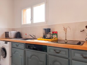 A kitchen with a washing machine, a coffee maker, and a bag of coffee.