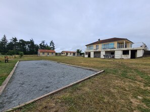 A residential area with a large open space, a gravel court, and a building with a balcony.