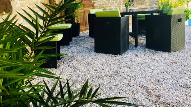 Een terras met rieten meubels en een muur van steen op de achtergrond.