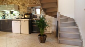 Een keuken met een stenen muur, een houten plafond en een trap naar een ander niveau.