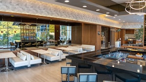 Recepció d'hotel moderna amb zona de bar, zones d'estar i grans finestres que donen a l'exterior.