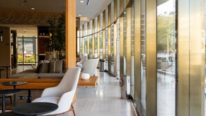 Rebedor modern d'hotel amb un llarg passadís, zones d'seure i grans finestres que donen vista a l'exterior.