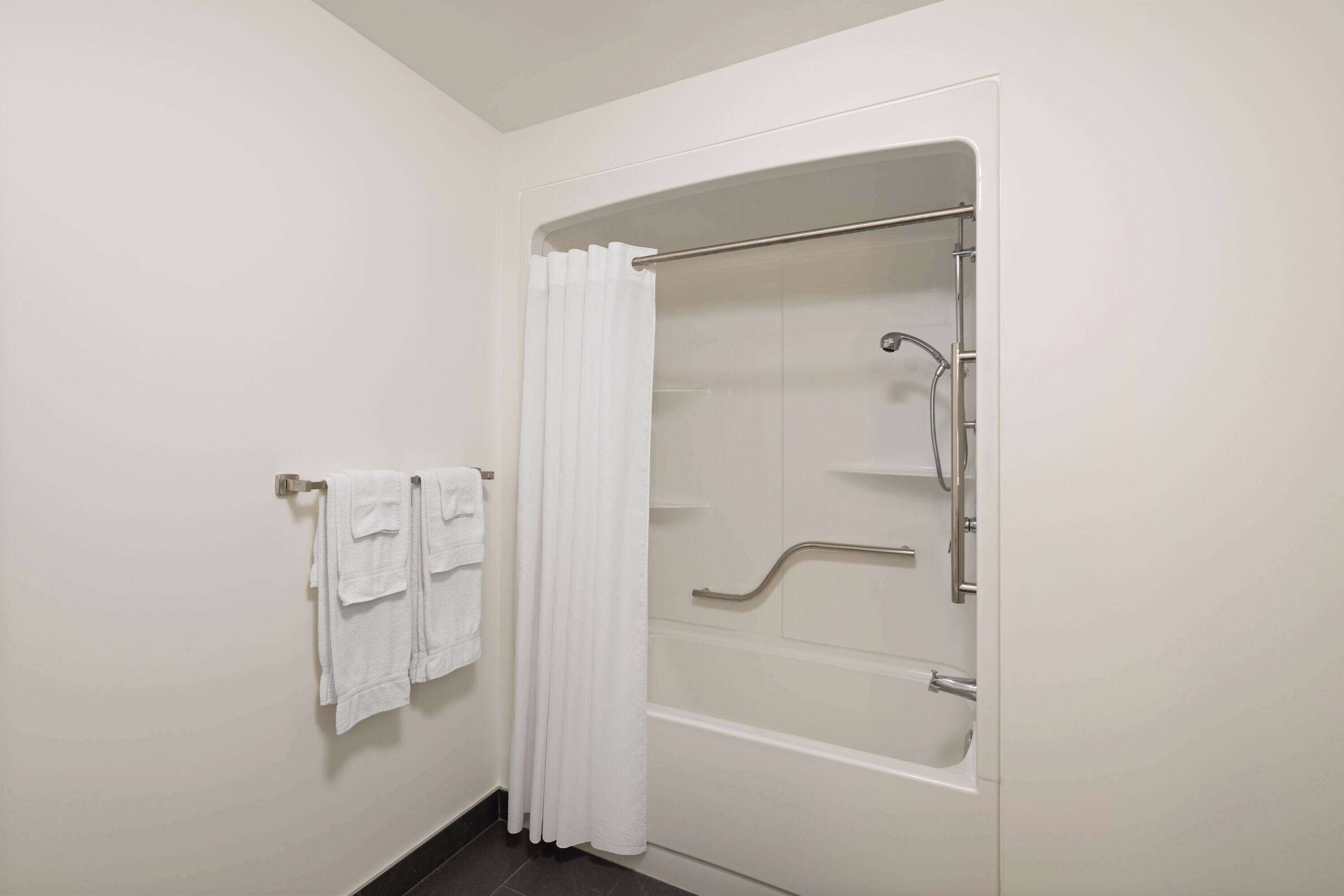Une salle de bain avec une douche à l’italienne, un porte-serviettes avec des serviettes pliées et une porte de douche en verre.