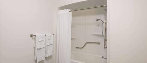 Une salle de bain avec une douche à l’italienne, un porte-serviettes avec des serviettes pliées et une porte de douche en verre.