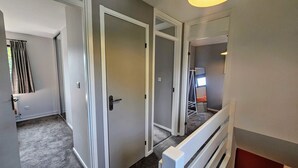 Un couloir avec des portes blanches, un miroir et un radiateur.