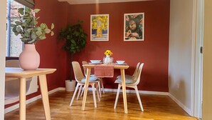 Un coin repas avec une table en bois, quatre chaises, un vase rempli de tournesols et deux œuvres d’art encadrées accrochées au mur.